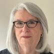 Headshot of a woman with silver hair and glasses